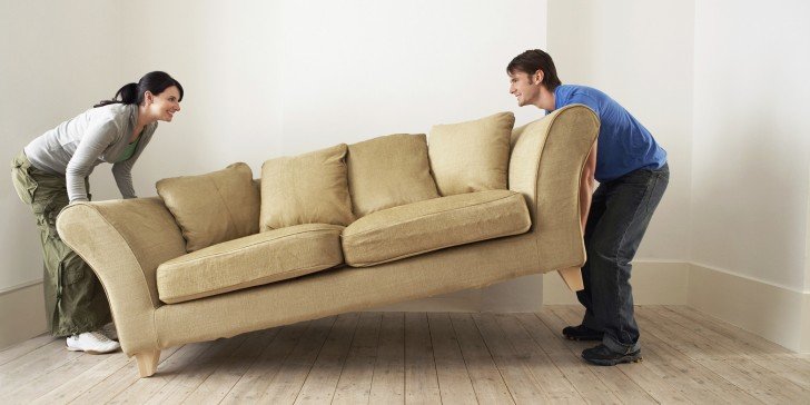 Couple Placing Sofa In Living Room Of New Home